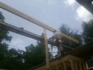 Carpenter setting a ridge beam over a new addition frame — Ice Dam Removal by Roofing Brothers in Hotchkiss