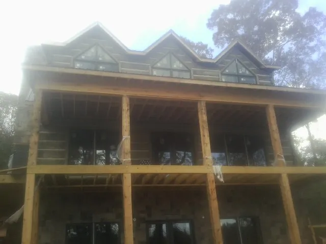 Dormers and porch framing on a large log home under construction — Roof Coating work by our crew in Hotchkiss