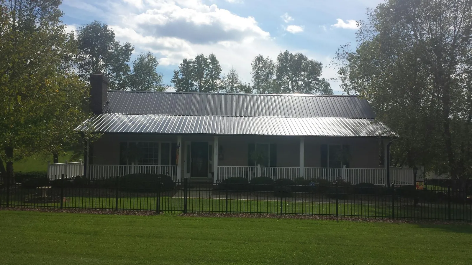 Gray metal roof on a brick ranch with a full width front porch — Gutter Guard Installation work by our crew in Hotchkiss