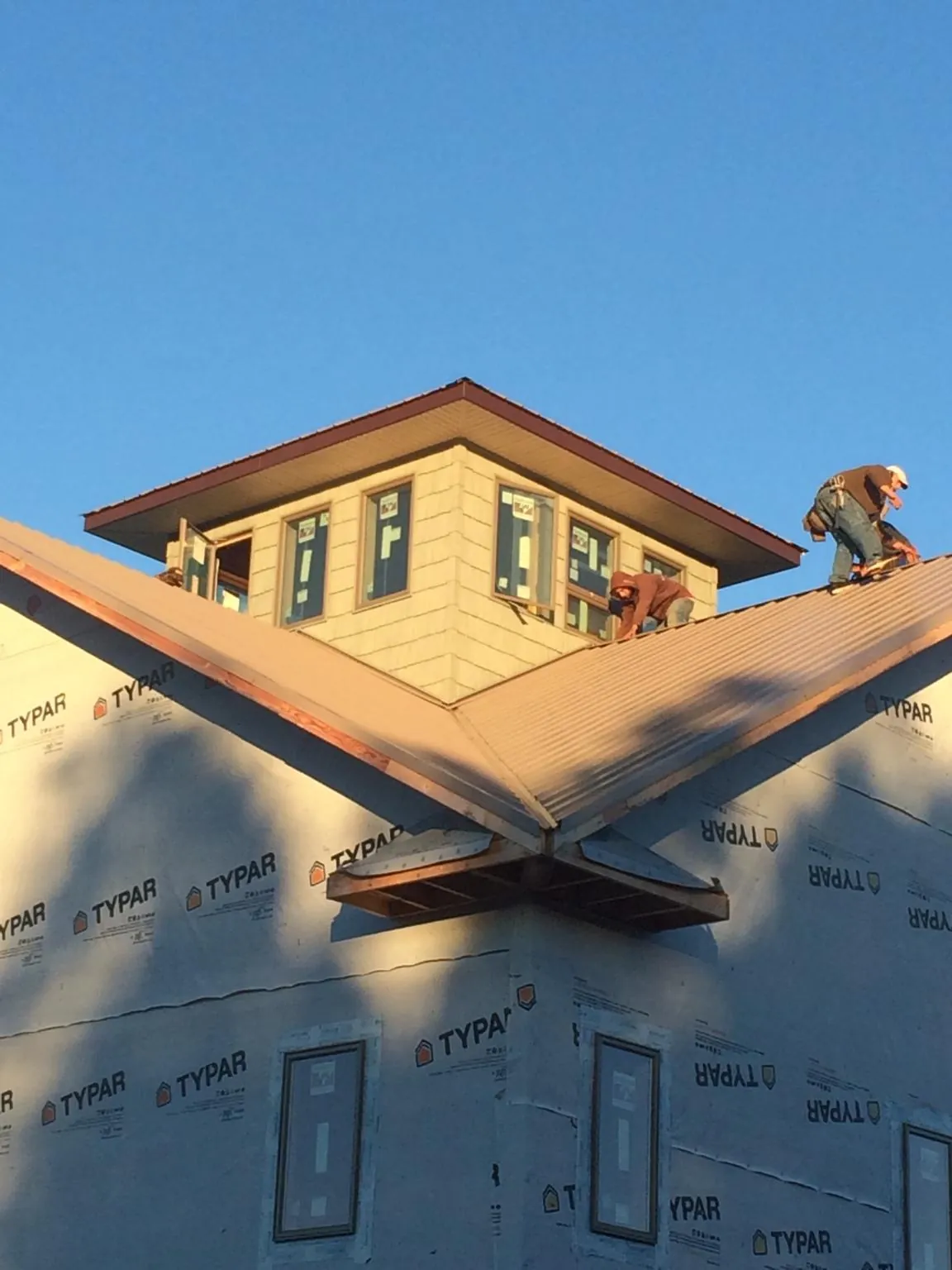 Roofers working around a rooftop cupola on a new metal roof at sunset — Roof Waterproofing in Hotchkiss by Roofing Brothers